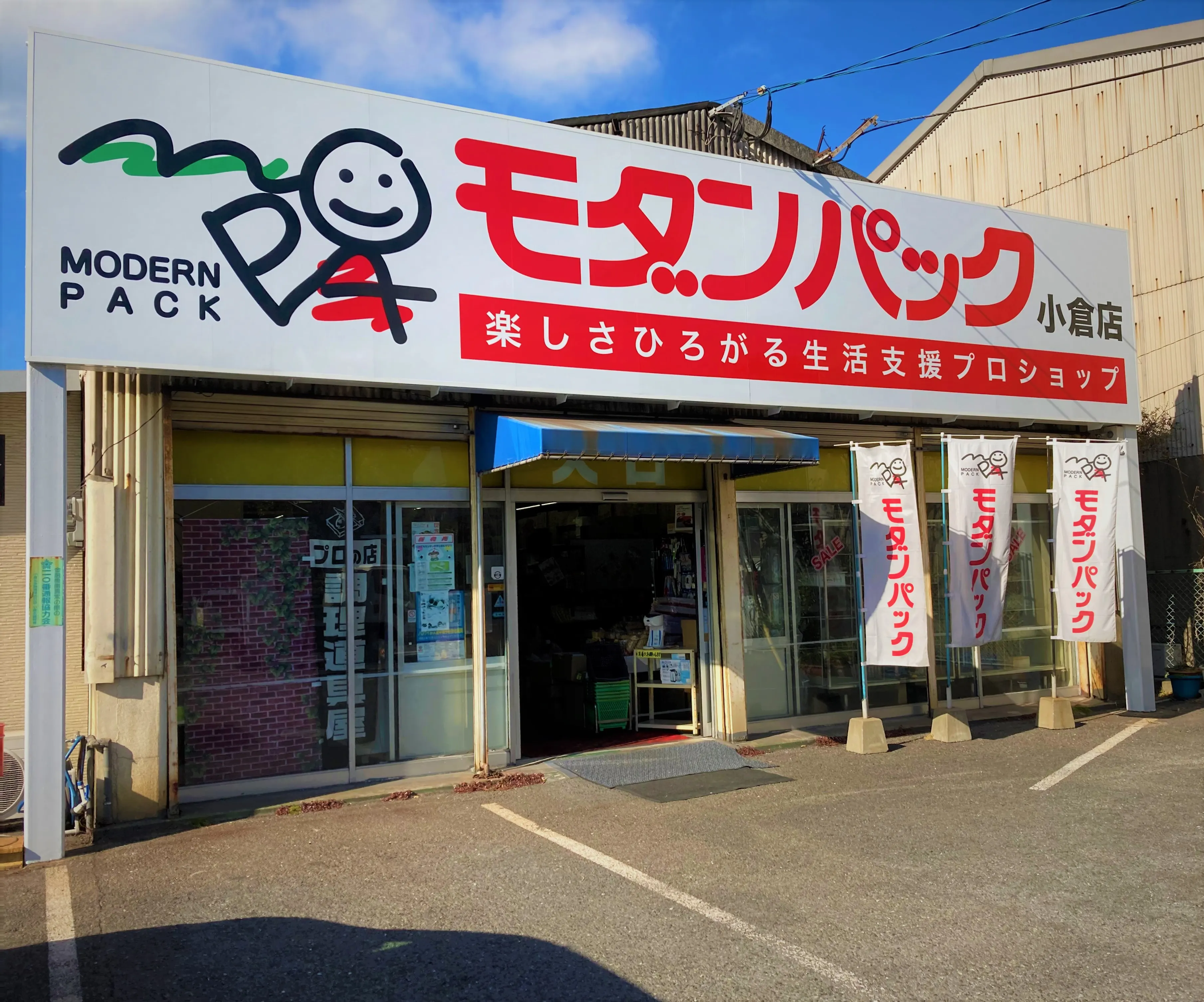 モダンパック・小倉店の外観。赤い文字の大きな看板とのぼり旗